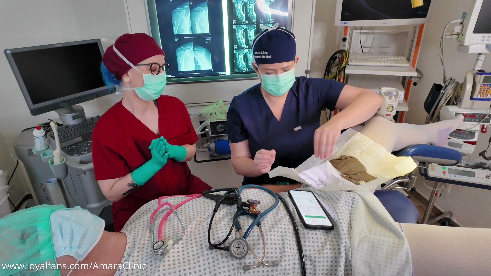 Mistress Katharina Amara teaching proper stethoscope auscultation to submissive nurse Miss Nena in the free Miss Nena medical BDSM video from Amara Fetish Clinic Belgium