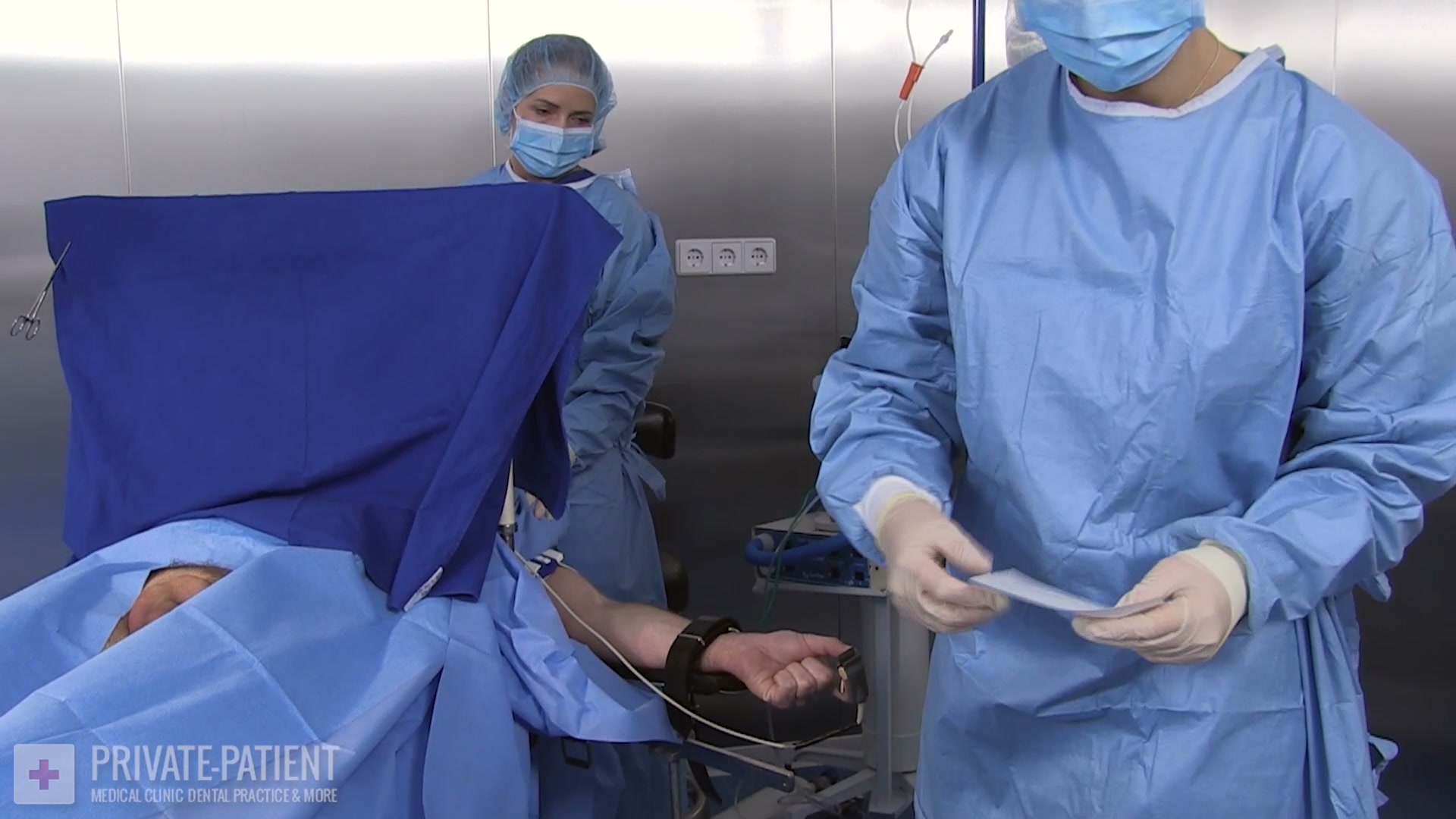 Draped private patient with his arm strapped to the table while Dr. Eve and Nurse Shiva prepare the second urinary calculi procedure in this free Private Patient medical bdsm video